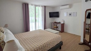 A hotel room with a bed, a desk, a chair, a TV, and a mirror. - Villa Manoé (Draguignan)