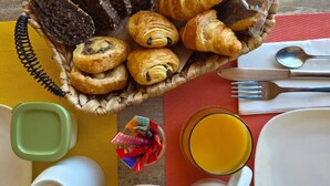 A breakfast setting with pastries, a glass of orange juice, and various breakfast items on a table. - Villa Manoé (Draguignan)