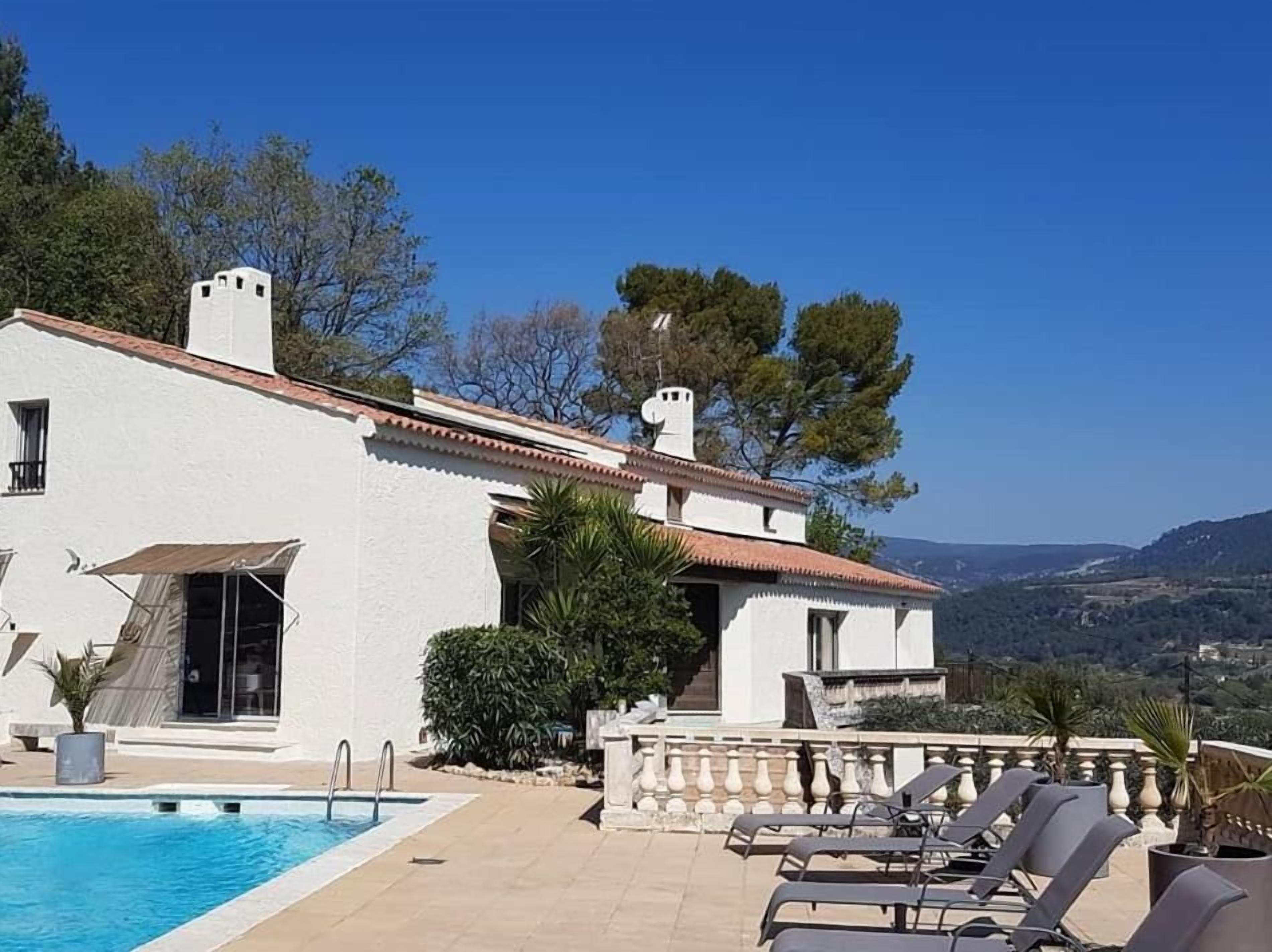 A villa with a swimming pool, outdoor seating, and a view of the landscape.