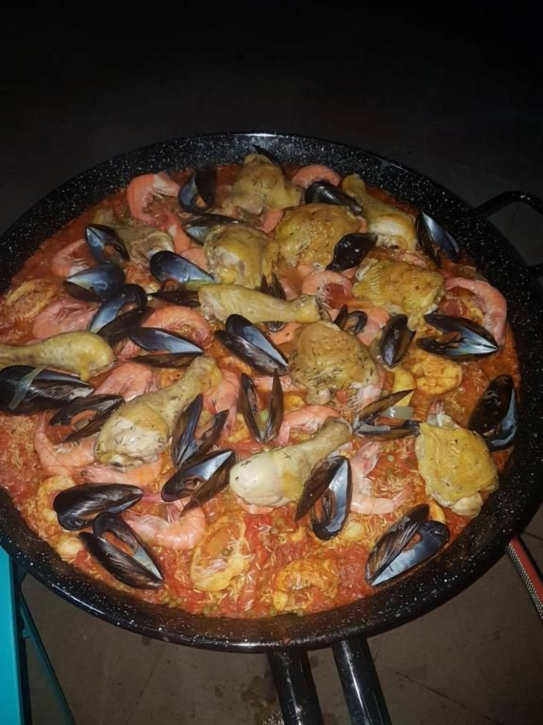 A large, round cooking pot filled with seafood, likely a seafood stew or paella.