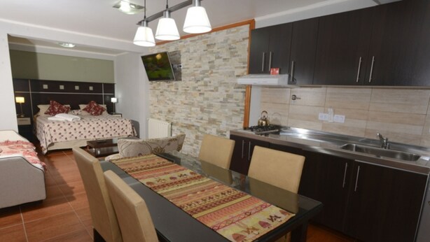 A modern kitchen with dark cabinets, a stainless steel sink, and a dining area with a glass table and chairs. - Ushuaia Apart Hotel Cabo San Diego (Ushuaia)