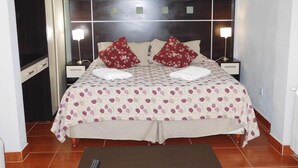 A neatly made bed with a polka dot bedspread, two pillows, and a remote control on a small table in front. - Ushuaia Apart Hotel Cabo San Diego (Ushuaia)