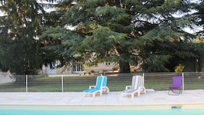 Una piscina con sillas de descanso y una valla.