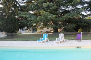Une piscine avec des chaises longues et une clôture.
