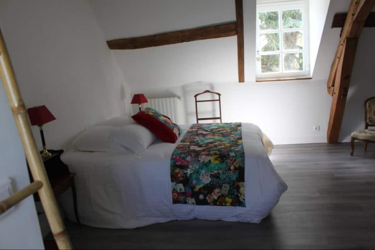 Ein Schlafzimmer mit einem Bett, einer roten Lampe, einem Fenster und einer Holzleiter.