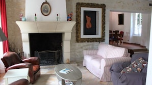 Una sala de estar con chimenea, un sofá a rayas, una mesa de centro y sillones de cuero.