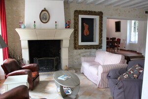 Un salon avec une cheminée, un canapé à rayures, une table basse et des fauteuils en cuir.