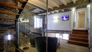 A modern interior with a staircase, stone walls, and a flat-screen TV. - Pensión Domus Gallery (Arzua)