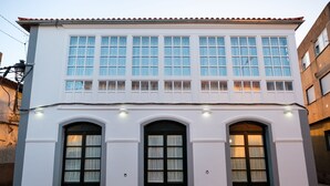 A two-story building with a white facade, large windows, and three arched doorways. - Pensión Domus Gallery (Arzua)