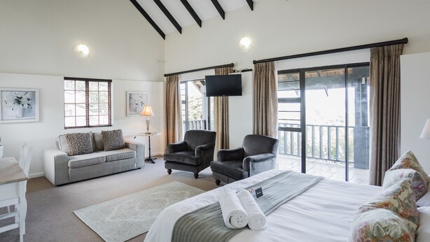 Een hotelkamer met een bed, twee fauteuils, een bank, een bureau en een televisie.