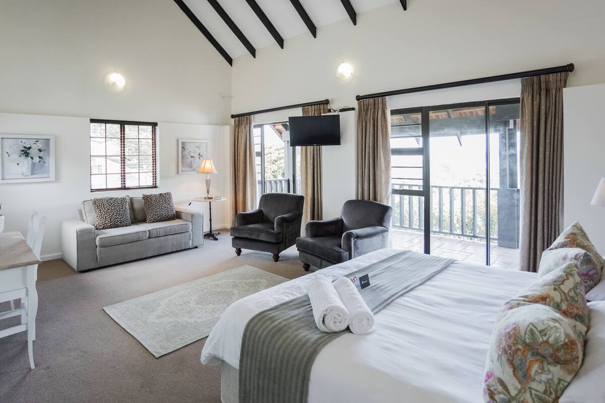 A hotel room with a bed, two armchairs, a sofa, a desk, and a TV.
