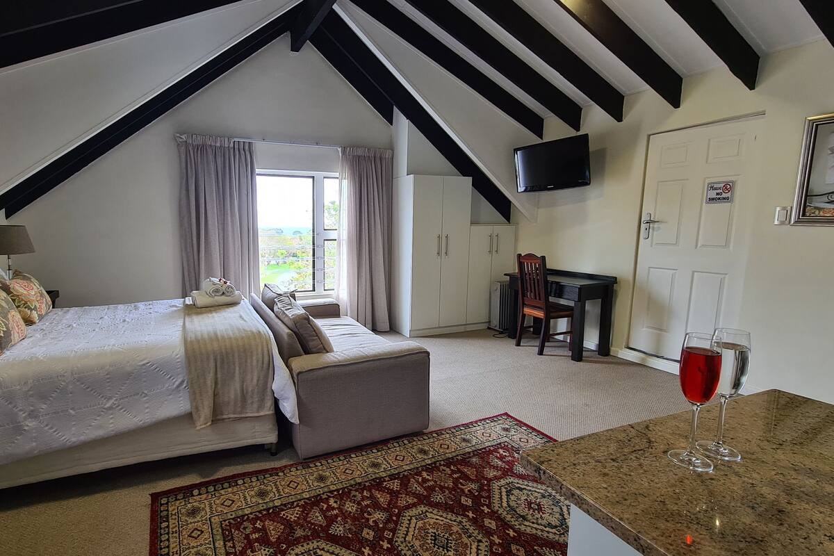 A bedroom with a bed, a desk, a chair, and a TV.