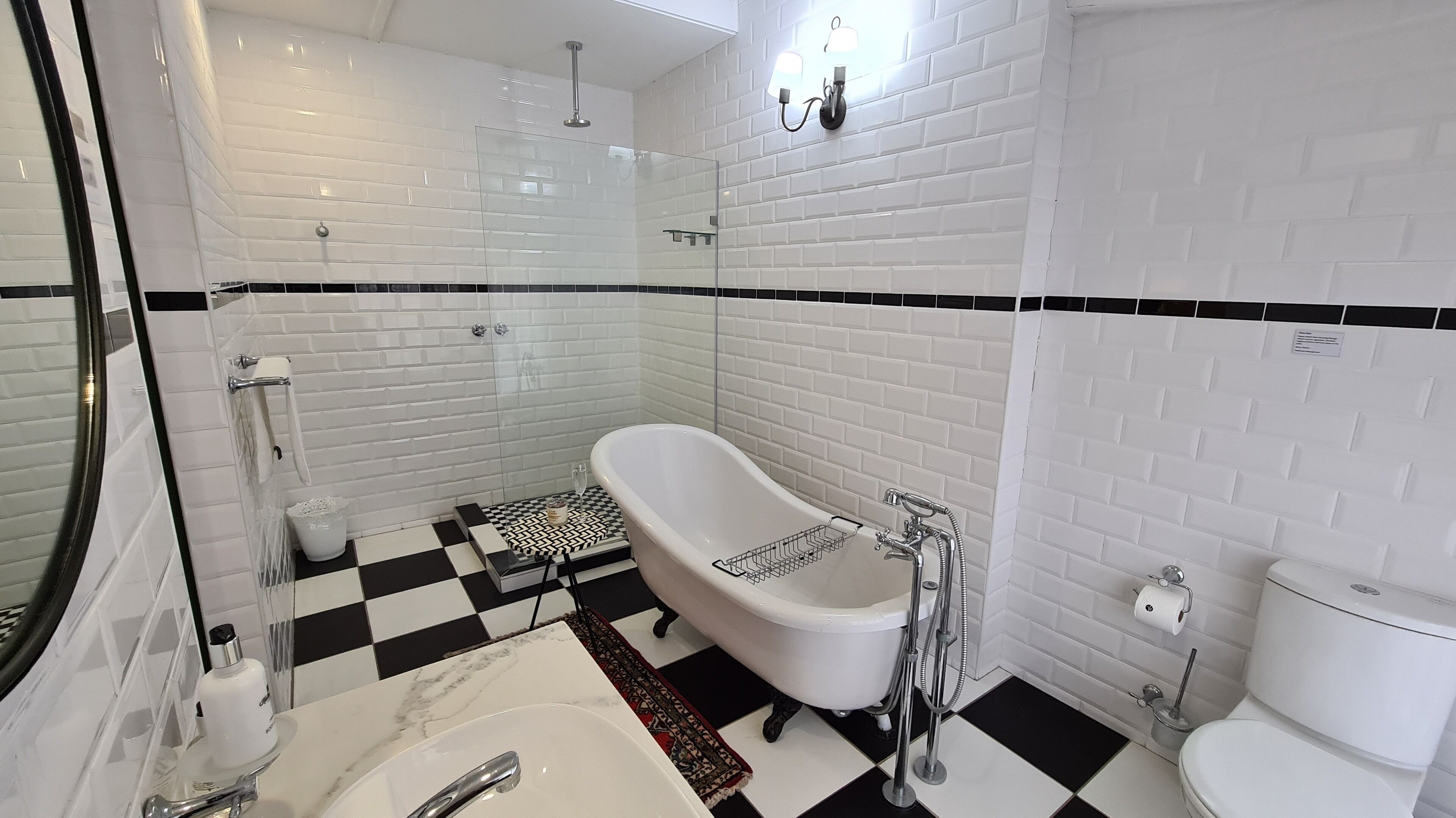 Ein Badezimmer mit einer weißen Badewanne, einer Duschkabine, einer Toilette und einem Schachbrettboden.