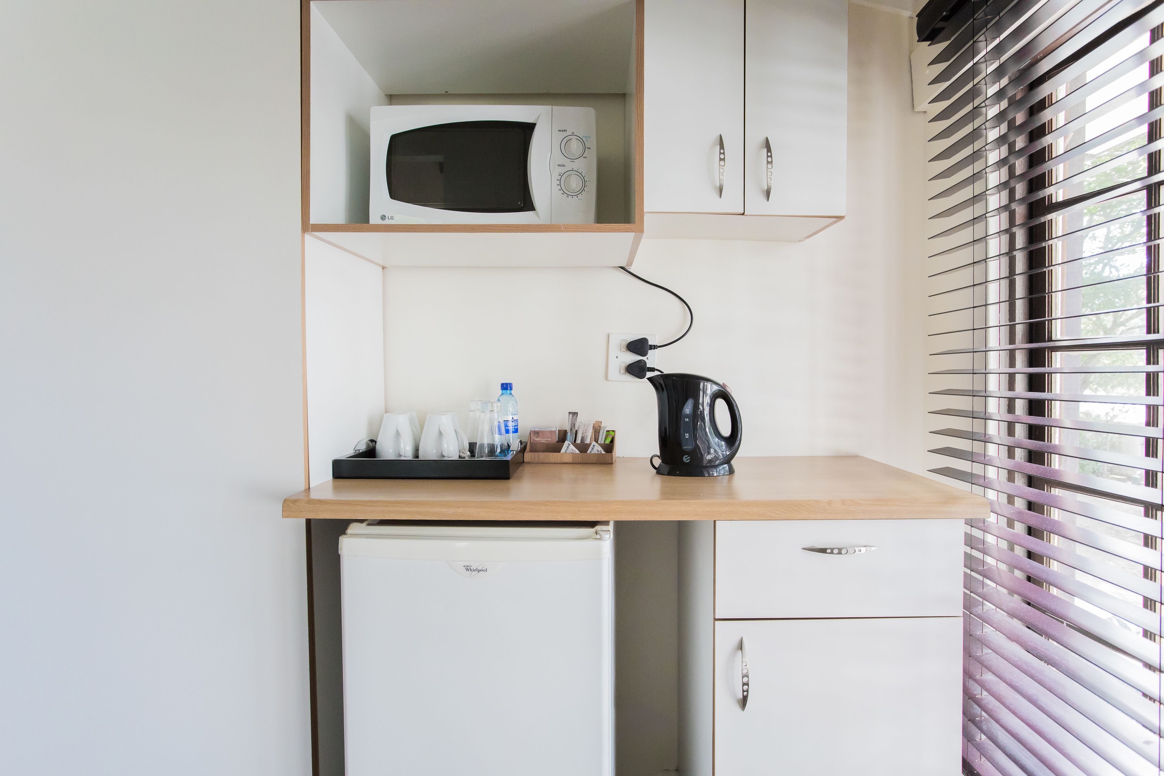 Une petite cuisine équipée d’un four à micro-ondes, d’une bouilloire et d’un réfrigérateur.