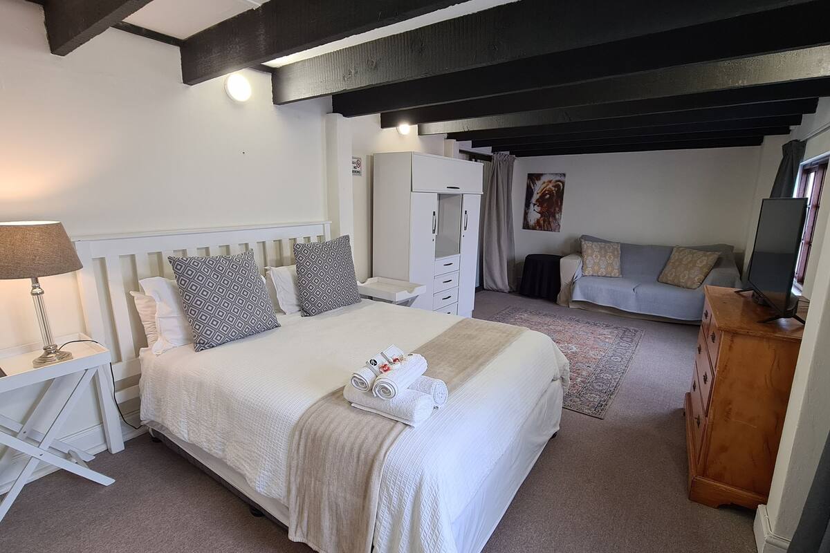 A bedroom with a bed, bedside table, lamp, wardrobe, and a television.