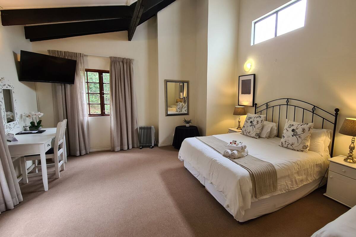 A bedroom with a bed, bedside tables, a desk, and a window with curtains.