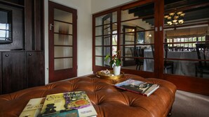 Een kamer met een bruine leren bank, een potplant en boeken erop.