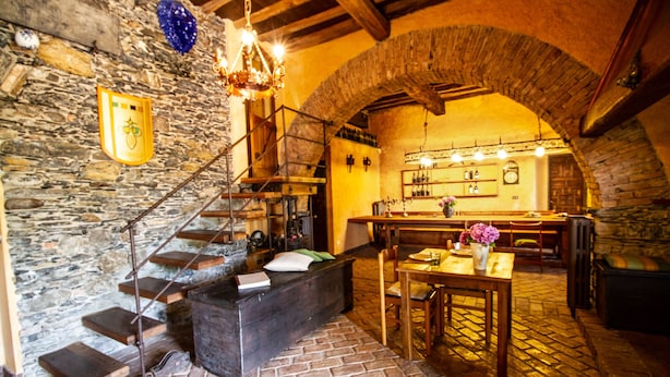 A rustic interior with stone walls, a wooden staircase, a dining area, and a bar. - B&B Rivarola al Tempo dei Castelli (Carasco)