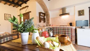 Une cuisine chaleureuse avec une table en bois, un panier de pain, une plante en pot et une machine à café.
