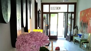 A hallway with a large pink hydrangea in a glass vase, a white lace doily, and a newspaper on a wooden table. - Hostal Montsoliu (Arbucies)