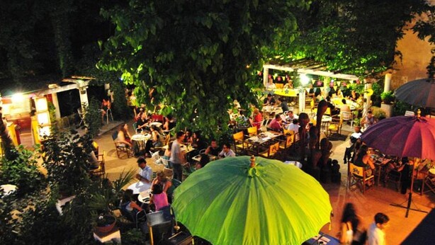 An outdoor dining area with tables and chairs, surrounded by greenery and trees. - Hostal Montsoliu (Arbucies)