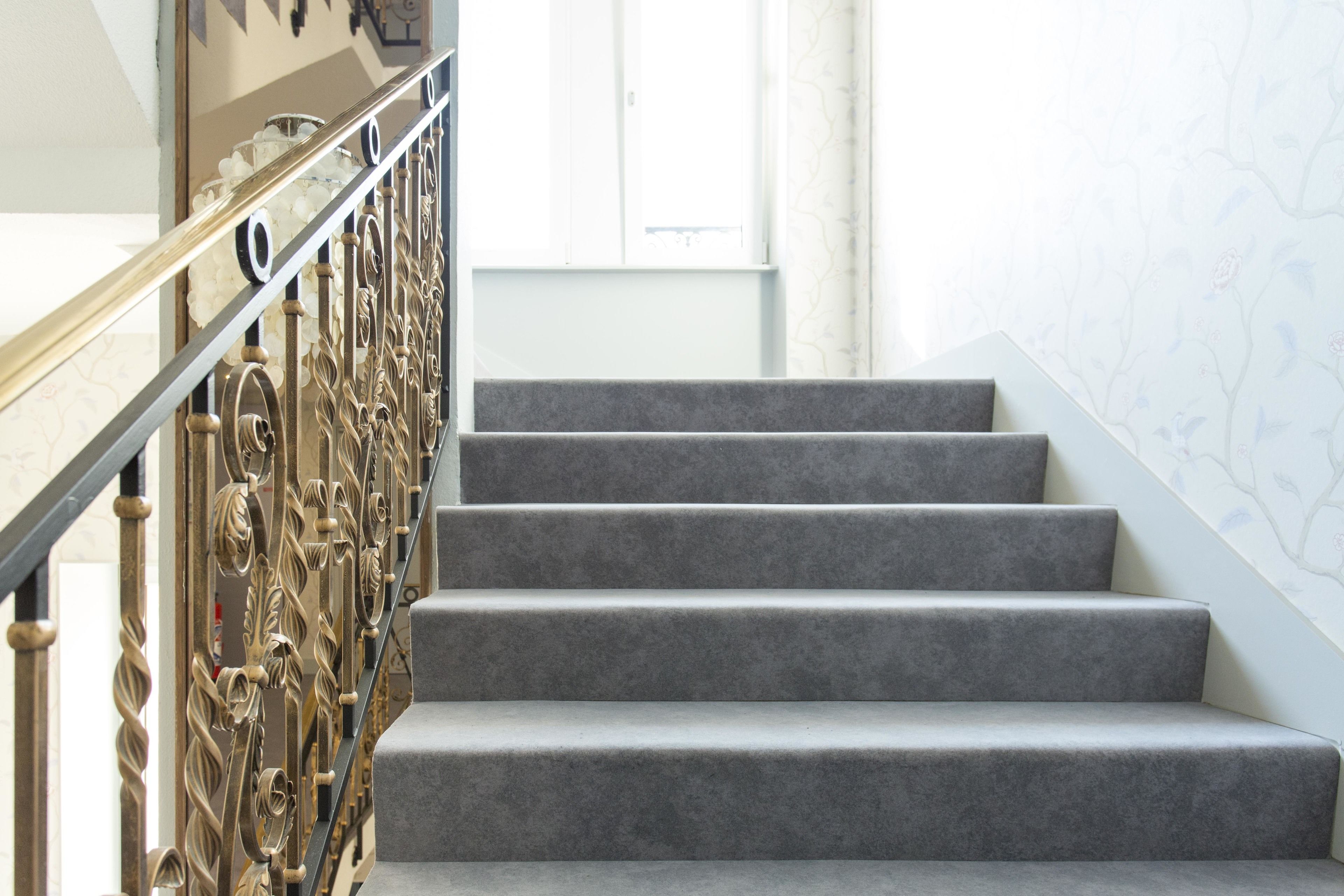 A staircase with a metal railing and carpeted steps.