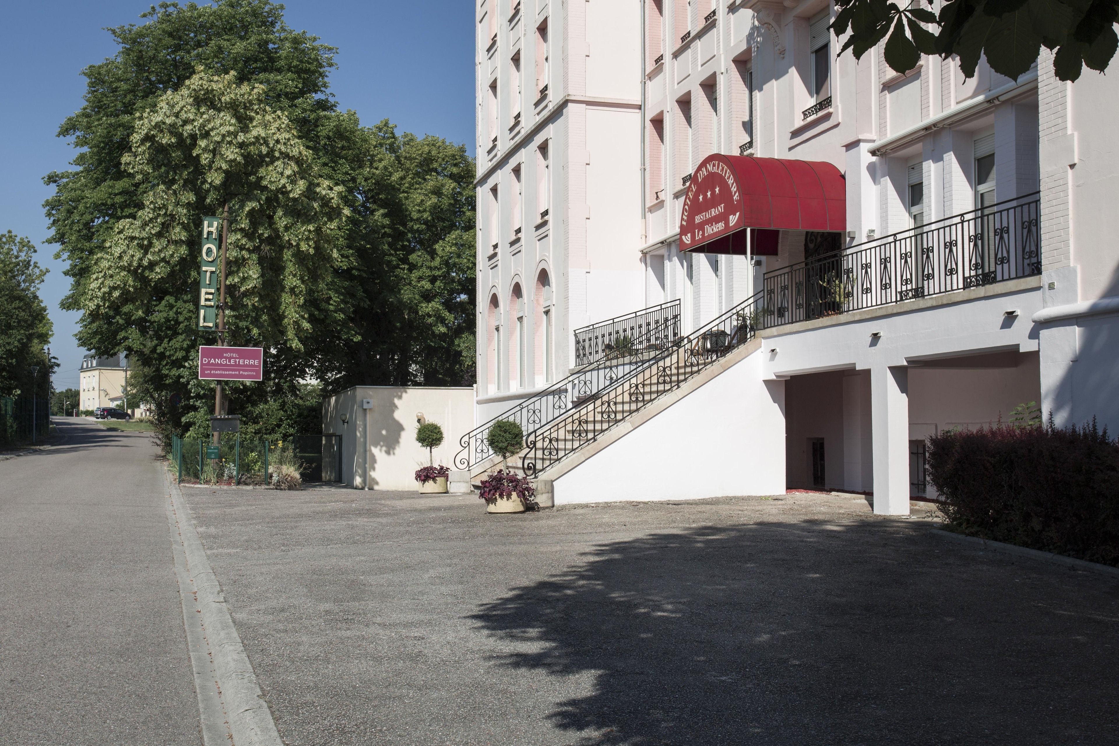A hotel with a red awning, a staircase leading to the entrance, and a sign indicating a restaurant on the ground floor.