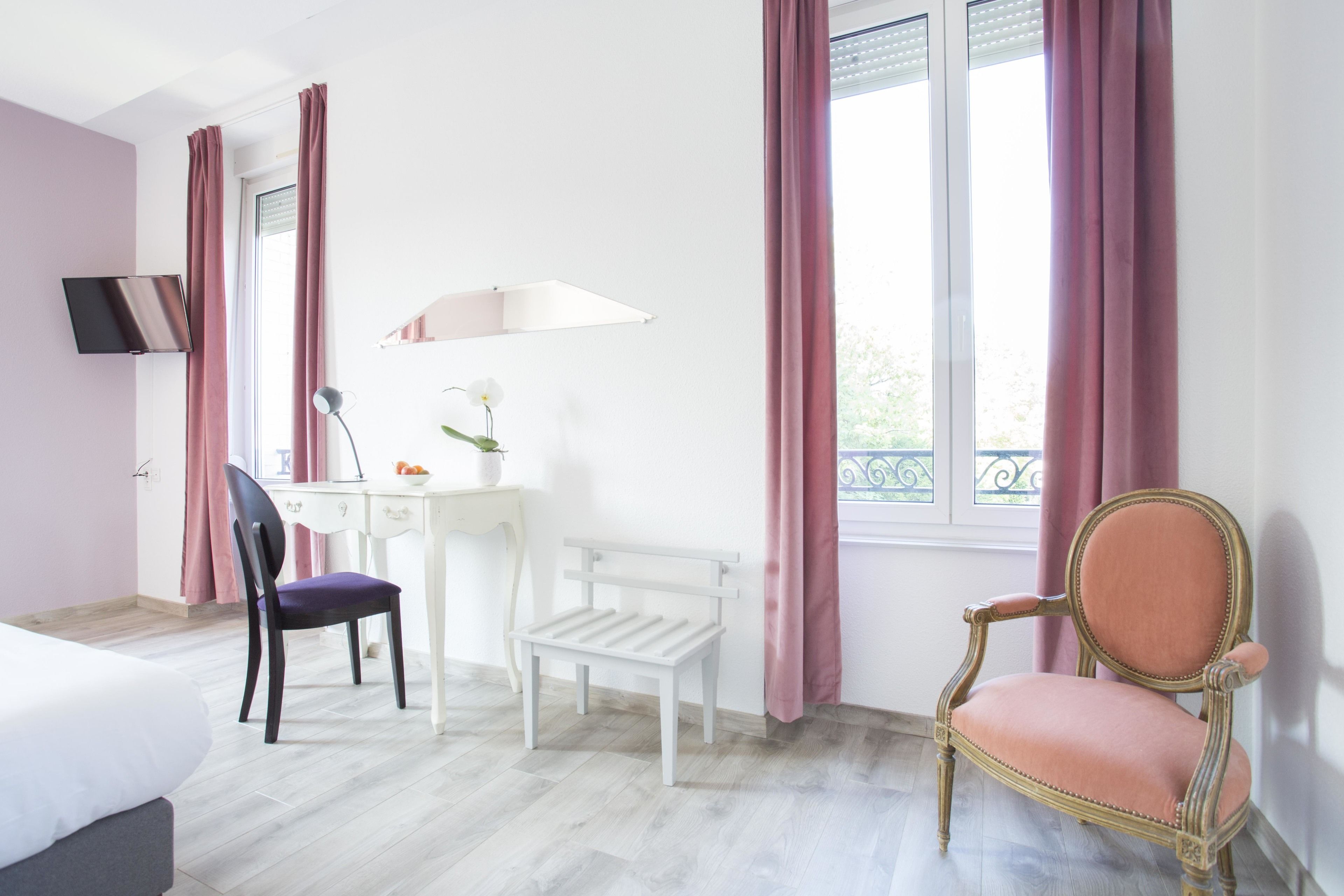 Ein Zimmer mit einem Bett, einem Schreibtisch mit Lampe, einem Stuhl und einem Fenster mit Vorhängen.