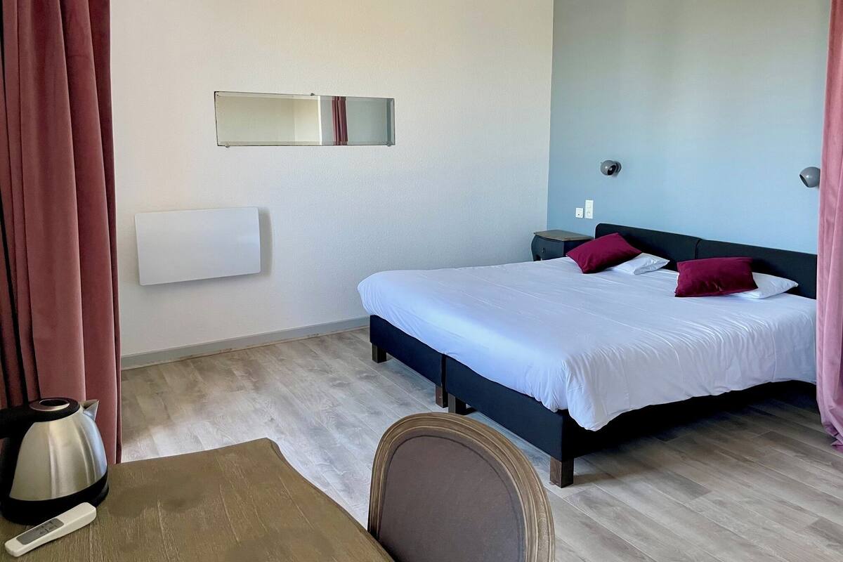 Una habitación de hotel con una cama, mesita de noche y una tetera.