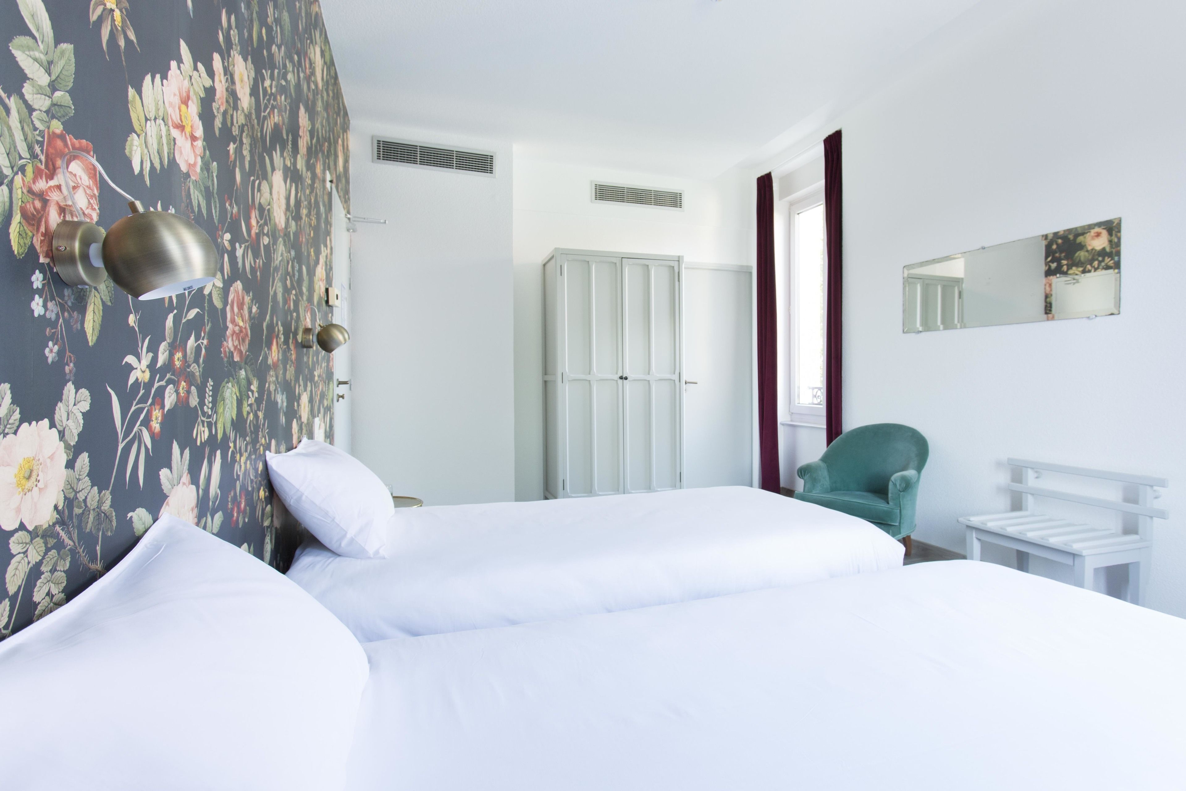 A hotel room with a bed, a wardrobe, a chair, and a small table.