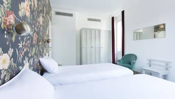 A hotel room with a bed, a wardrobe, a chair, and a small table.