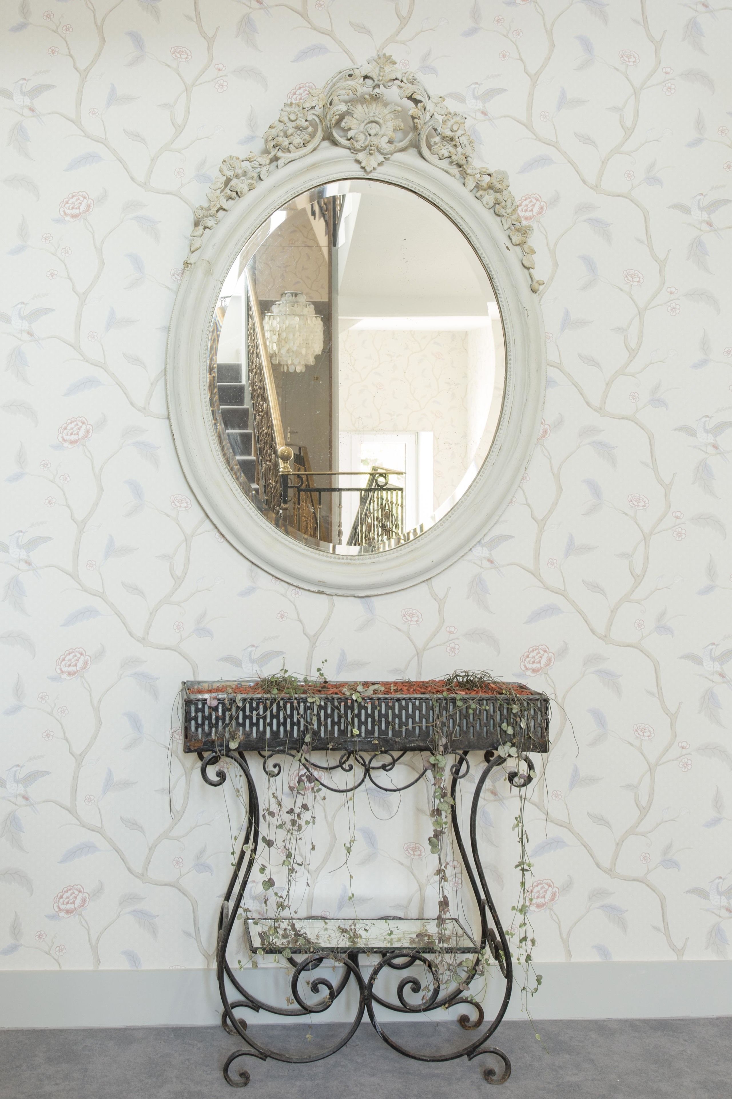 A mirror with an ornate frame and a decorative console table below it.