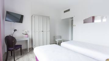 A bedroom with a bed, a desk with a chair, a television, a wardrobe, and a small table with a potted plant.