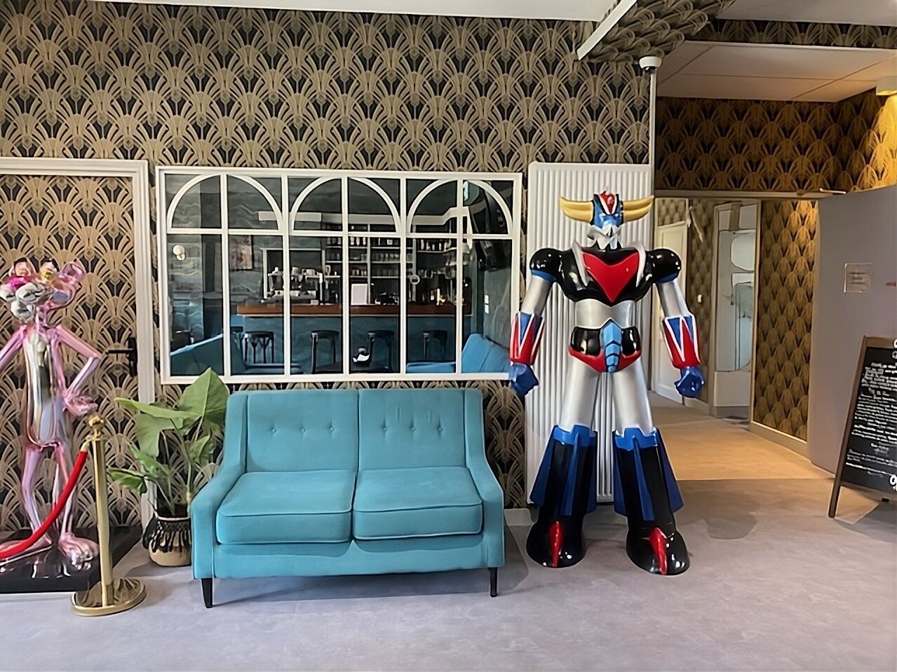 A blue sofa, a large window, and a statue of a character.