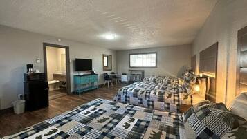 Une chambre avec deux lits, un bureau, une chaise, une télévision et une fenêtre.