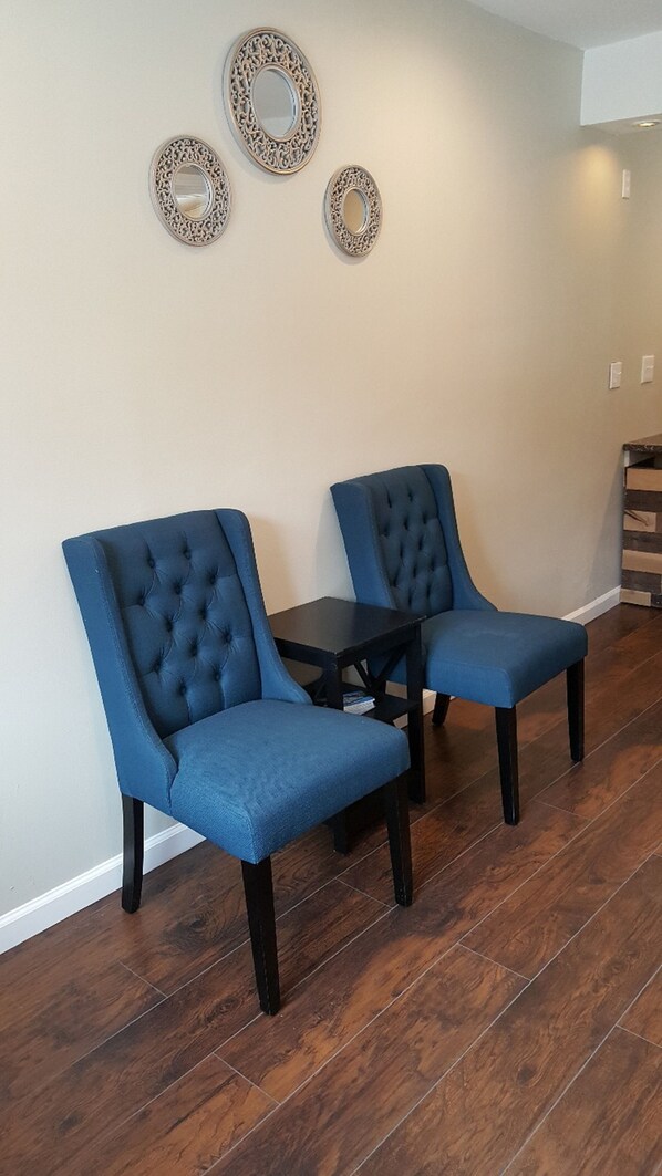 A room with two blue tufted chairs, a small black table, and three decorative wall mirrors. - Lake Ridge Hotel (South Lake Tahoe)