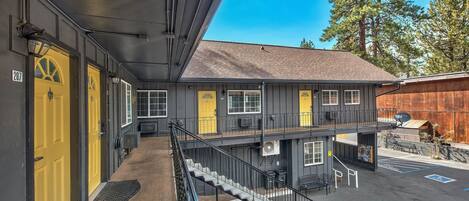 A two-story motel with yellow doors, a covered outdoor area, and a parking lot.
