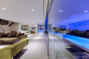 A modern interior with a sofa, dining area, and a glass partition.