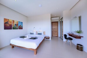 Een moderne slaapkamer met een groot bed, nachtkastjes, een bureau en een spiegel.