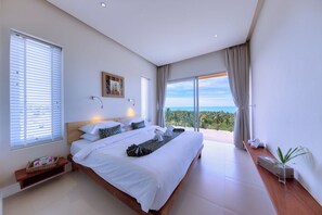 A modern bedroom with a large bed, a view of the ocean, and a balcony with a potted plant.