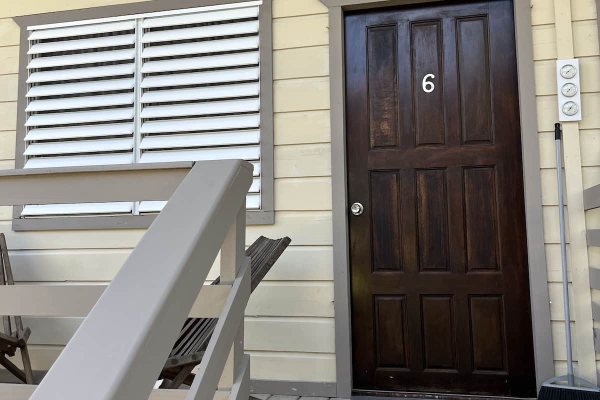 A wooden door with the number 6, a window with blinds, and a wooden deck.
