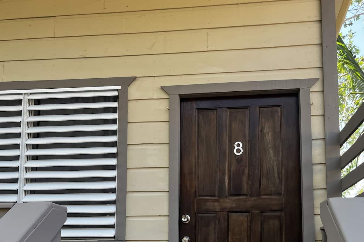 A wooden door with the number 8, a bench, and a window with blinds.