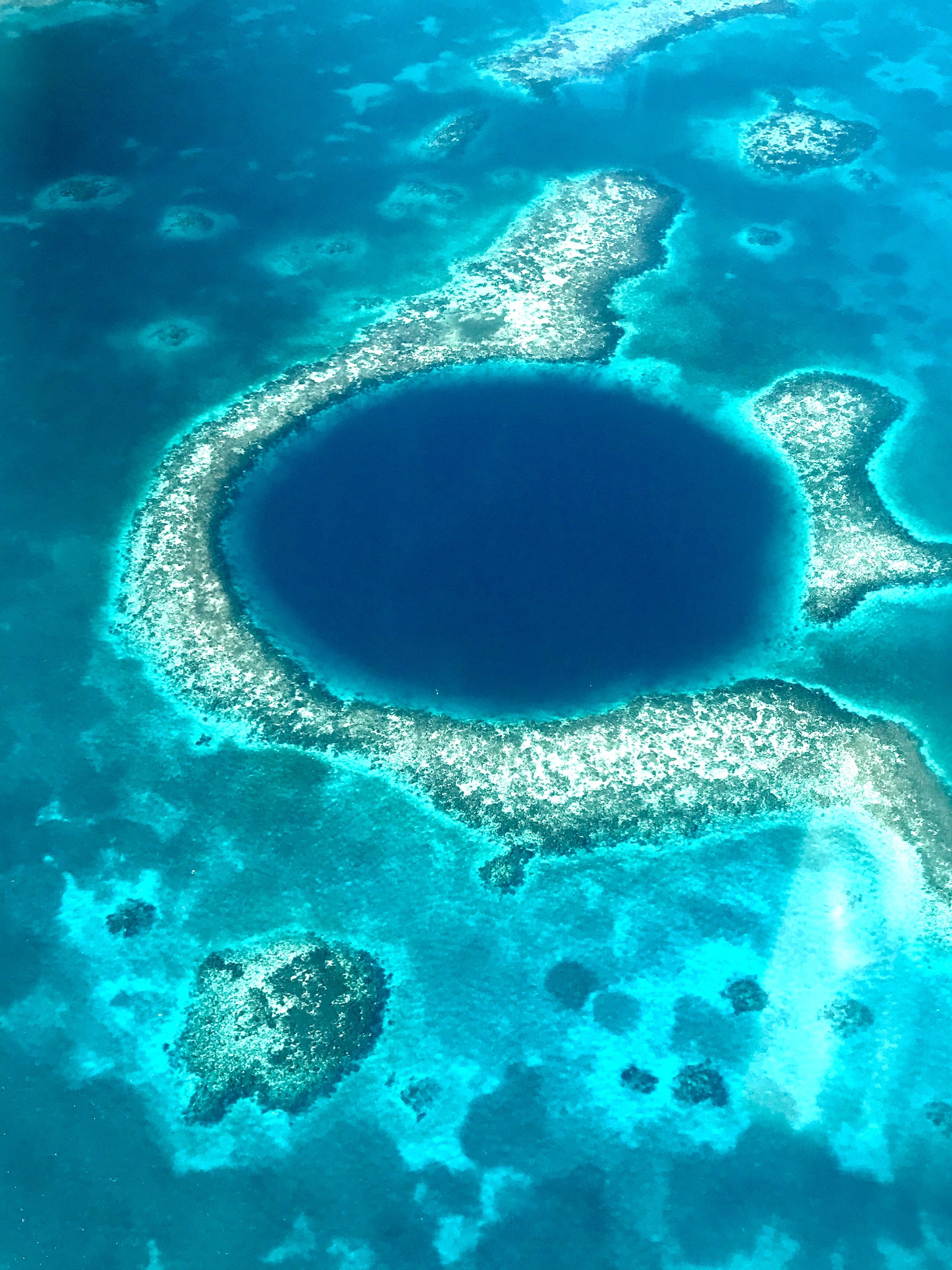 Vue aérienne d’une barrière de corail, avec des eaux d’un bleu limpide et plusieurs petites îles.