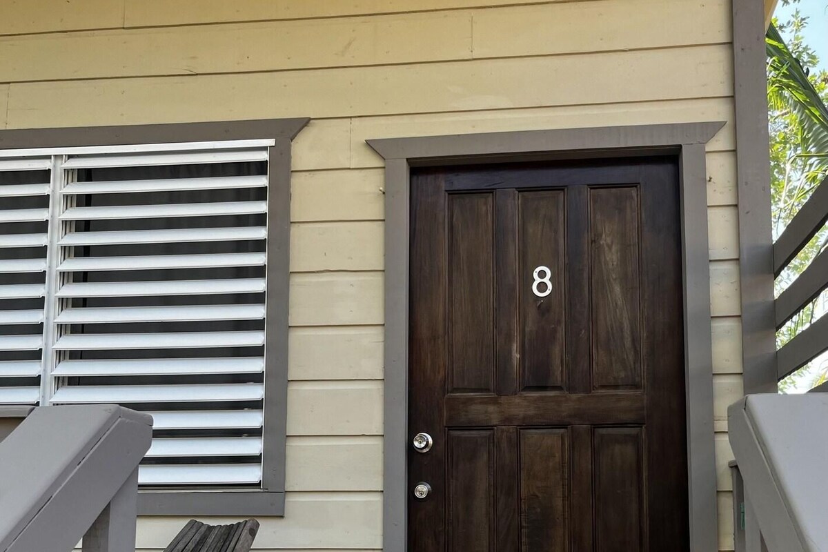 A wooden door with the number 8, a porch with a bench, and a window with blinds.