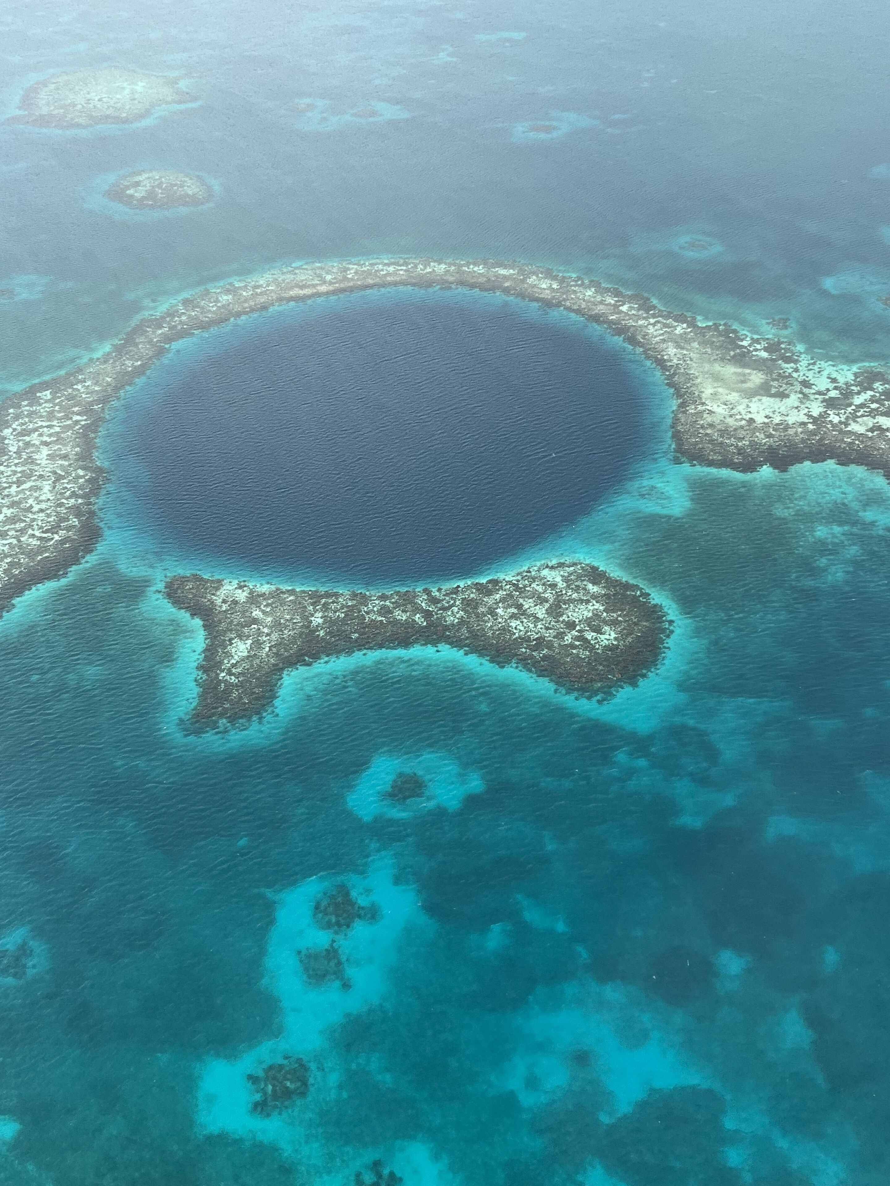 Vista aérea de una extensa laguna circular rodeada de arrecifes de coral y pequeñas islas.