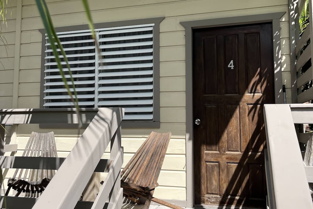 A wooden porch with a bench, a door marked with the number 4, and a window with blinds.