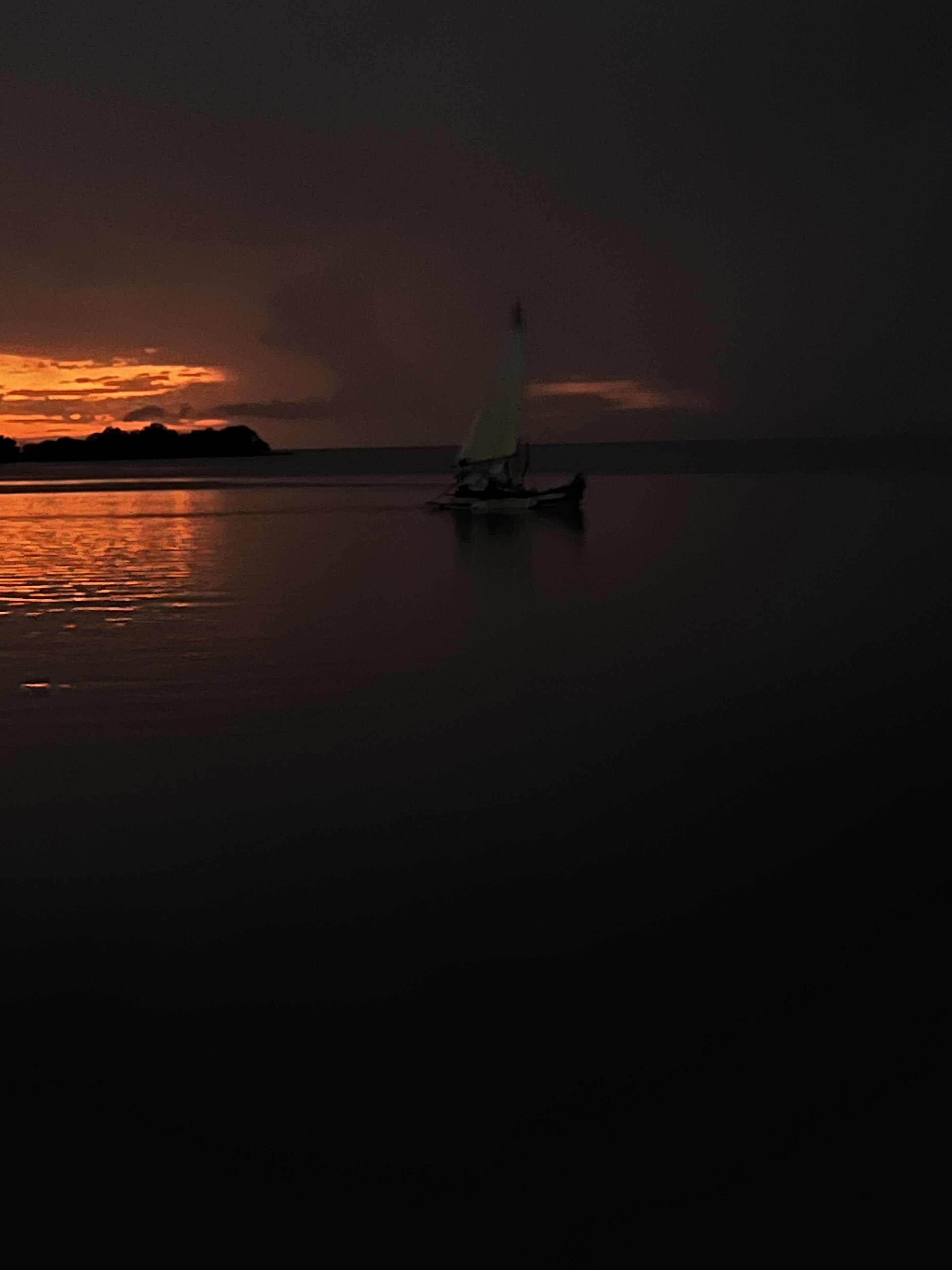 A sailboat on calm water during sunset.