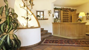 A staircase with a decorative plant, a wooden cabinet, and a patterned rug. - Hotel Frey (Ismaning)