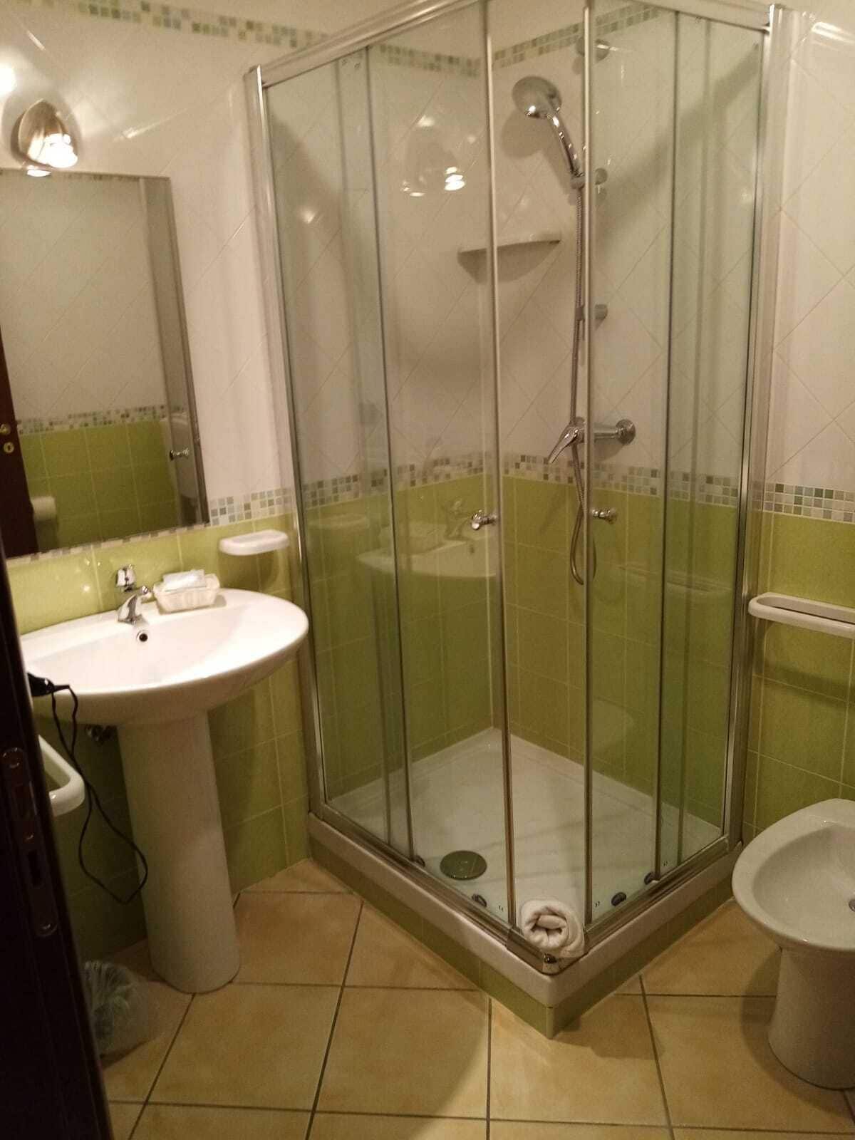 Un baño con ducha envuelta en vidrio, un lavabo y un bidé.