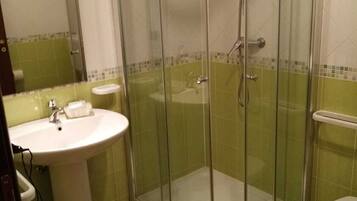 Un baño con ducha envuelta en vidrio, un lavabo y un bidé.
